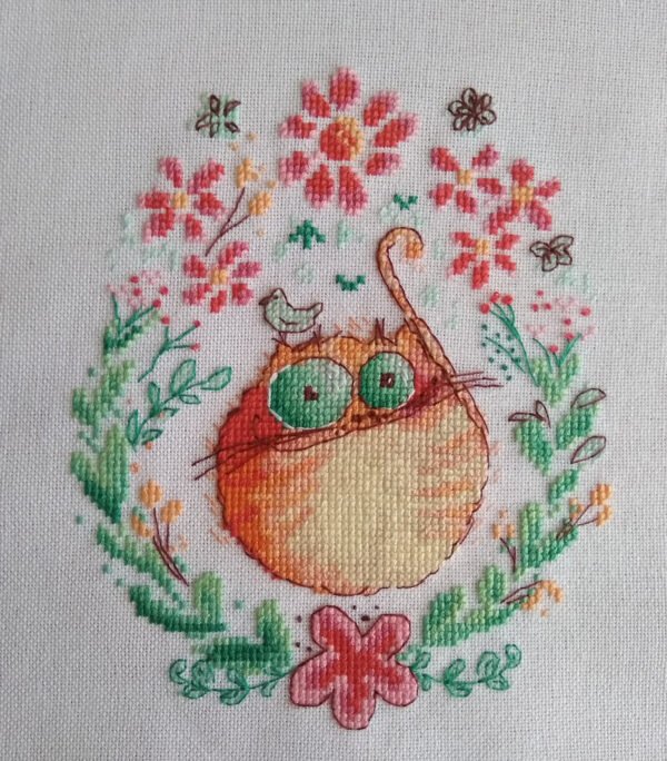 finished embroidery of cross stitch artwork with floral ginger cat surrounded by colorful flowers and soft decorative details