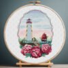 Summer lighthouse cross stitch with floral peonies and coastal scenery in embroidery hoop