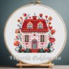 Cross stitch pattern of a fairy spring house displayed in a wooden embroidery hoop with floral folk art details
