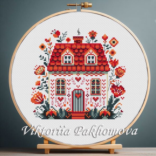 Cross stitch pattern of a fairy spring house displayed in a wooden embroidery hoop with floral folk art details