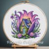 Purple fairy house cross stitch pattern displayed in a wooden embroidery hoop with lavender floral details