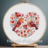 131 Birds Heart cross stitch pattern displayed in a wooden embroidery hoop with Scandinavian floral motifs