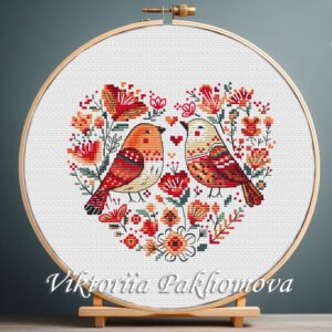 131 Birds Heart cross stitch pattern displayed in a wooden embroidery hoop with Scandinavian floral motifs