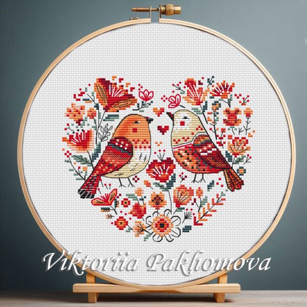 131 Birds Heart cross stitch pattern displayed in a wooden embroidery hoop with Scandinavian floral motifs