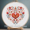 Floral Heart cross stitch pattern displayed in a wooden embroidery hoop with Scandinavian folk motifs