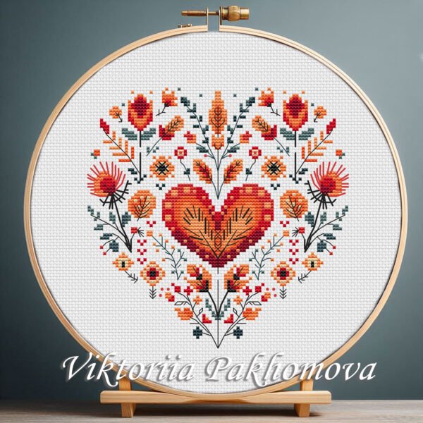 Floral Heart cross stitch pattern displayed in a wooden embroidery hoop with Scandinavian folk motifs