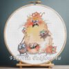 Cross stitch embroidery of a large ginger cat surrounded by playful kittens in bright colors, displayed in a wooden hoop