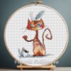 Cross stitch embroidery of a ginger cat and a white mouse with bright colors and playful details, displayed in a wooden hoop