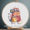131 Cross stitch embroidery of four colorful whimsical cats with large expressive eyes, displayed in a wooden hoop.