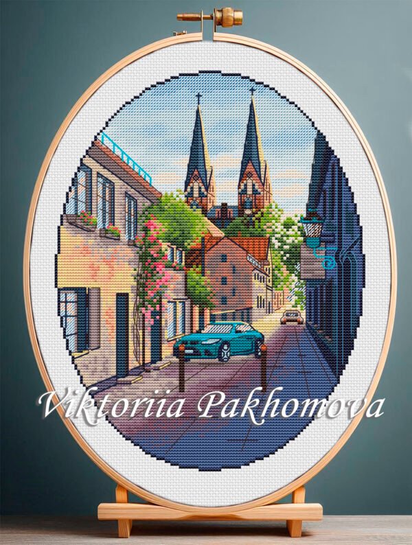 Neuruppin Germany cross stitch pattern with European cityscape and blue car in embroidery hoop