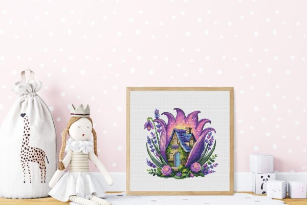 Framed cross stitch artwork of a purple fairy house surrounded by lavender flowers and summer greenery
