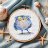 Whimsical Tawny Owl cross stitch pattern displayed in a wooden embroidery hoop with pastel bird details