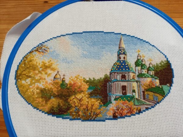 Kyiv monastery cross stitch displayed with autumn leaves and cozy decor, vibrant Ukrainian embroidery