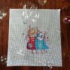 finished cross stitch artwork featuring two romantic cats with bright colors, tiny birds and soft decorative elements