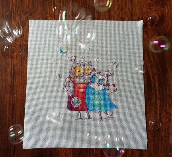 finished cross stitch artwork featuring two romantic cats with bright colors, tiny birds and soft decorative elements