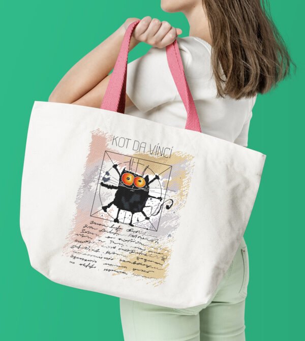 Finished cross stitch artwork of a humorous black cat in a Da Vinci‑style pose with bold lines and soft background tones on tote bag