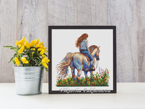 Finished embroidery of girl on horse surrounded by flowers — nature cross stitch artwork