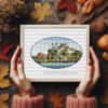 Framed Swiss castle cross stitch artwork with mountains and water, scenic European embroidery