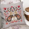 Romantic bunny cross stitch design displayed on decorative pillow