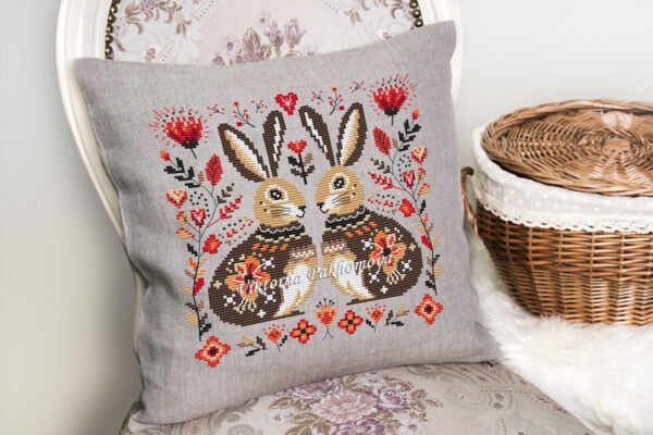 Romantic bunny cross stitch design displayed on decorative pillow