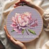 Peony flower cross stitch pattern in embroidery hoop with purple and pink petals