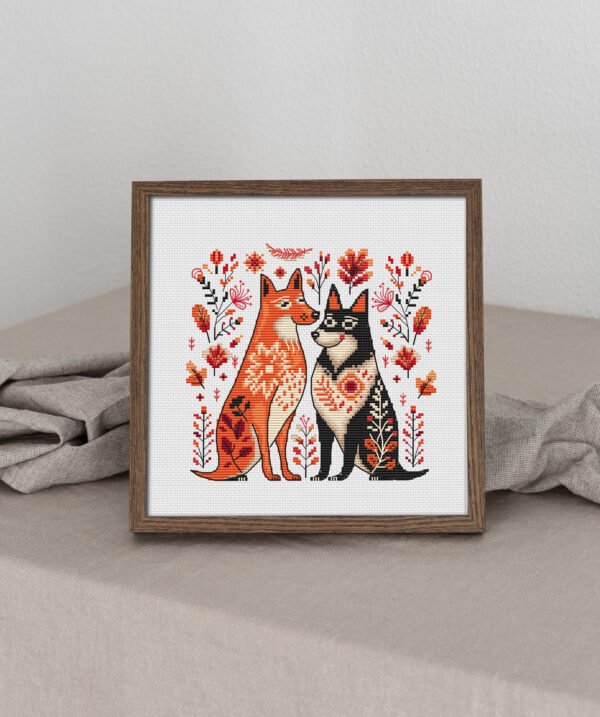Framed cross stitch artwork of two romantic folk‑art dogs surrounded by Scandinavian floral motifs