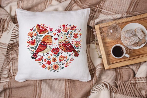 White linen pillow, cushion Mockup on plaid. Inrerior photo Birds heart cross stitch design displayed on decorative pillow