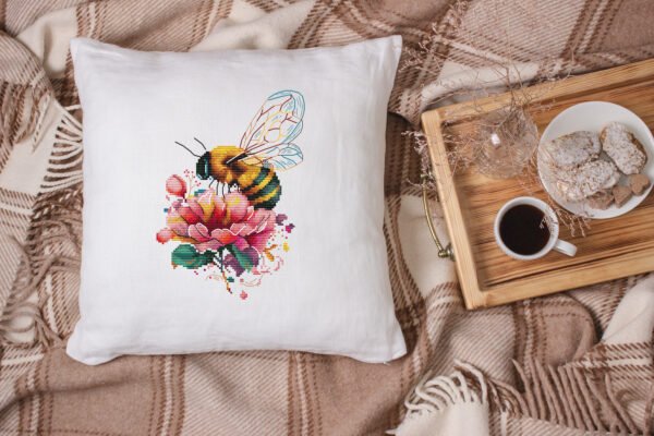 Peony and bee cross stitch design displayed on decorative pillow for cozy room décor