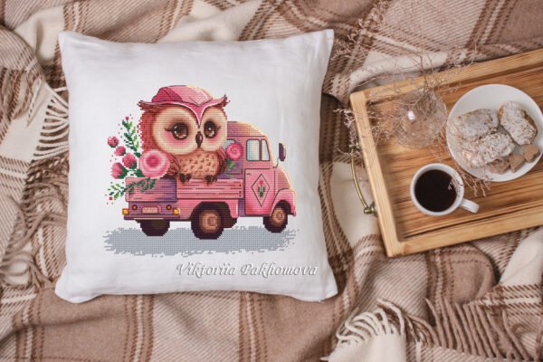 Baby owl and pink truck cross stitch artwork surrounded by plush toys, colorful children’s decor