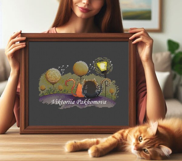 Framed cross stitch artwork featuring two cats in love with warm colors, dreamy trees and gentle decorative elements