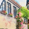 Close‑up of Neuruppin city cross stitch with buildings, flowers, and blue car