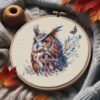 Mystical owl cross stitch in wooden hoop with autumn leaves and yarn, warm seasonal embroidery setup