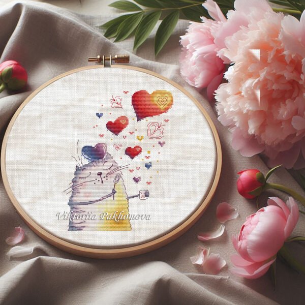 Cross stitch embroidery of a romantic whimsical cat surrounded by colorful hearts, displayed in a wooden hoop