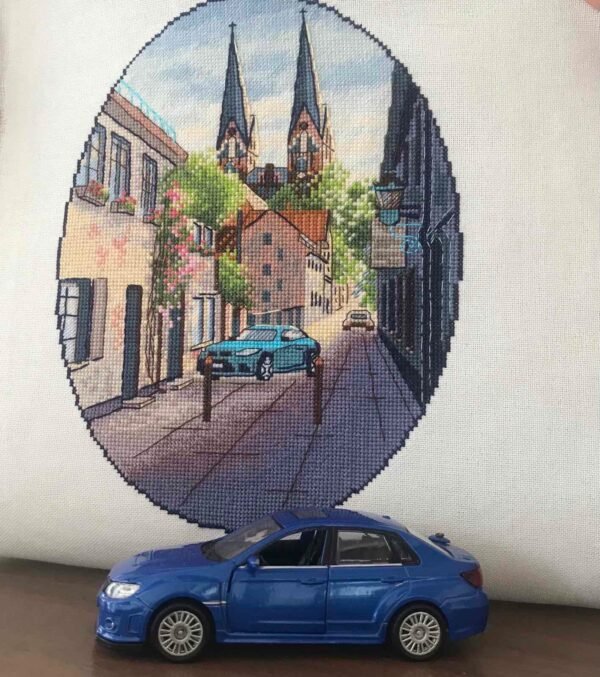 Finished embroidery of Neuruppin Germany cross stitch pattern with European cityscape and blue car