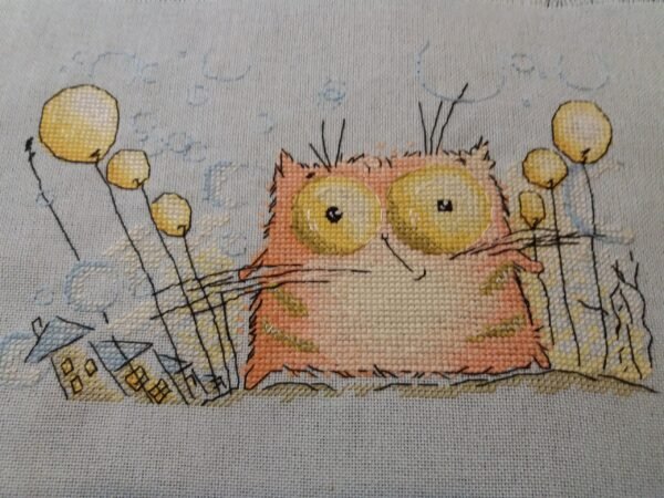 finished cross stitch artwork featuring a cute whimsical ginger kitten with colorful details and a cheerful nursery style.