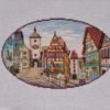 Framed Rothenburg Germany cross stitch displayed with cozy decor, vibrant medieval town embroidery