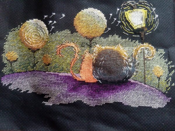 finished cross stitch artwork featuring two cats in love with warm colors, dreamy trees and gentle decorative elements