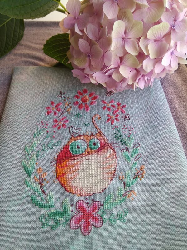 finished embroidery of cross stitch artwork with floral ginger cat surrounded by colorful flowers and soft decorative details