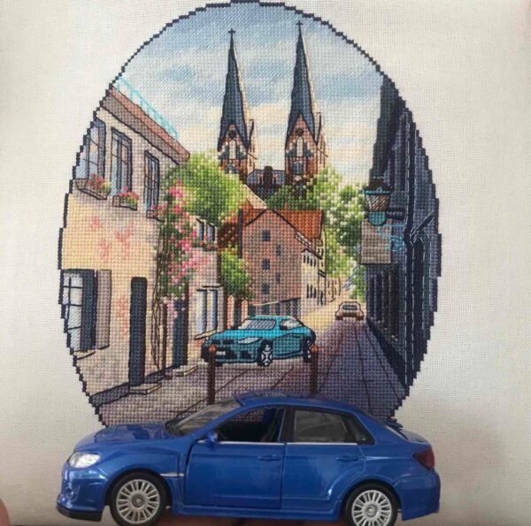 Finished embroidery of Neuruppin Germany cross stitch pattern with European cityscape and blue car