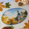 Kyiv monastery cross stitch displayed with autumn leaves and cozy decor, vibrant Ukrainian embroidery