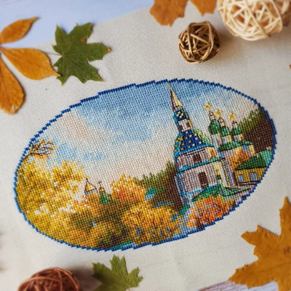 Kyiv monastery cross stitch displayed with autumn leaves and cozy decor, vibrant Ukrainian embroidery