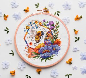 Spring bee cross stitch pattern in a wooden hoop with colorful flowers and honeycomb details