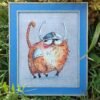 framed cross stitch artwork of a Viking‑themed ginger cat with expressive details and warm colors.