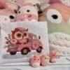 Baby owl and pink truck cross stitch artwork surrounded by plush toys, colorful children’s decor