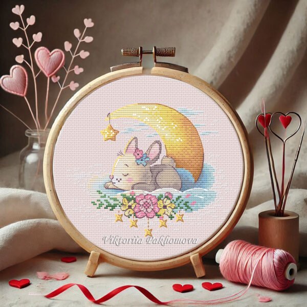 Cross stitch embroidery of a sleeping bunny displayed in a wooden hoop