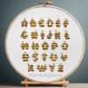 125 Cross stitch embroidery of a colorful bumblebee alphabet with bee‑shaped letters displayed in a wooden hoop