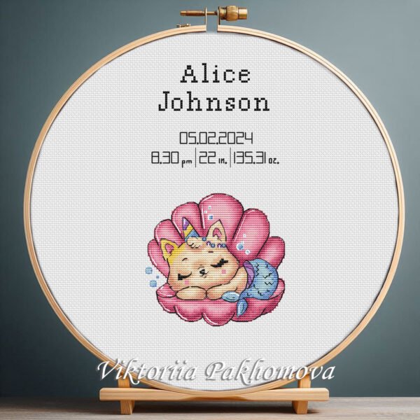 Cross stitch embroidery of a Mermaid Cat birth announcement with space for name, date and stats in a wooden hoop