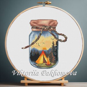 Cross stitch embroidery of a glass jar with a tent, campfire and forest landscape held in a wooden hoop