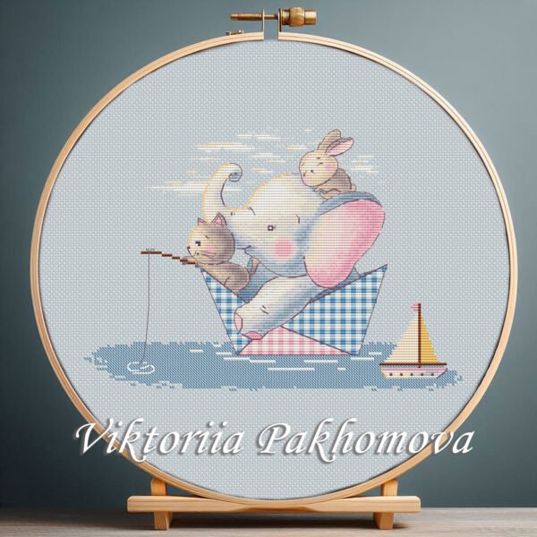 Cross stitch embroidery of an elephant, a bunny and a cat sitting in a small paper boat with soft pastel details in a wooden hoop