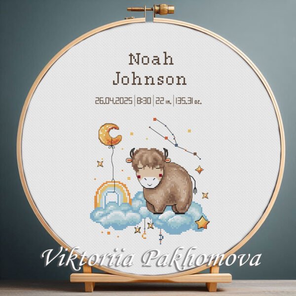 Cross stitch embroidery of a Baby Taurus zodiac birth announcement displayed in a wooden hoop with personalized newborn details.